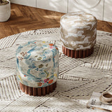 Two round upholstered ottomans on a patterned area rug in a styled interior. One ottoman has a beige and white horse pattern, and the other has a multicolor floral and bird print.