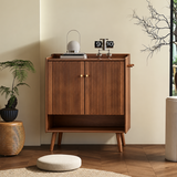 Walnut-finish shoe cabinet beneath a round mirror, with gold-tone door knobs, side hooks and a raised-edge top.
