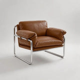 A modern armchair with brown leather cushions and a chrome tubular metal frame, photographed on a light gray studio background.