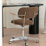 Rear view of a brown boucle office chair showing the metal back supports, wooden arm pads and castor base.