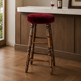 Burgundy-cushioned wooden bar stool beside a wood-panelled counter with a white stone top and a glass of red wine.