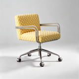 A modern office chair with a yellow fabric upholstered seat and backrest covered in white polka dots, supported by a chrome metal frame and five-wheel base.