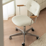 Angled top view of an ivory boucle office chair showing the padded seat, wooden arm pads and five-star castor base.