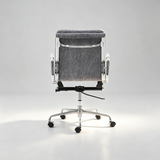 A modern office chair with a gray textured mesh backrest, chrome metal frame, white armrests, and a black five-star wheeled base, photographed against a light gray studio background.