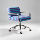 A modern office chair with a striped purple and teal bouclé upholstered seat and back, supported by a chrome five-star base with casters, shown on a light gray studio background.