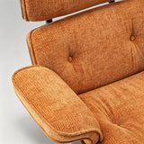 Close-up of a mid-century modern lounge chair upholstered in a warm rust-orange textured fabric, showing the tufted backrest, armrest, and button details against a light gray background.