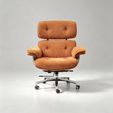 An orange upholstered lounge chair with a tufted backrest and armrests, mounted on a chrome five-star wheeled base, photographed against a light gray studio background.