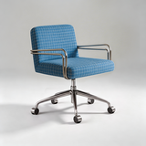 A modern office chair with a blue and white grid-patterned fabric upholstery, chrome metal armrests and base, and black caster wheels, photographed on a light gray studio background.