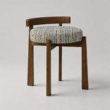 A mid-century modern wooden dining chair with a curved backrest, solid medium-brown legs, and a round upholstered seat cushion featuring a multicolor geometric pattern on a light beige background.
