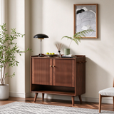 Walnut-finish shoe cabinet with slatted double doors and an open lower shelf, topped with a leafy vase and decorative bowl.
