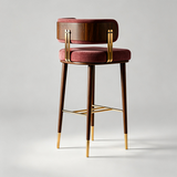A luxury bar stool with a deep burgundy velvet cushioned seat and backrest, dark walnut wood legs and backrest frame, and polished brass hardware and leg caps, shown on a light gray studio background.