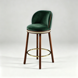 Dark green Alma bar stool with a curved upholstered backrest, dark wood legs and a gold-tone circular footrest.
