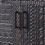 Close-up of geometric carvings and rectangular black handles on the cabinet's double doors.