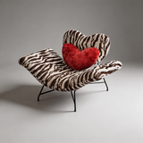 Brown and cream zebra-print lounge chair with a heart-shaped backrest, red heart cushion and black metal legs.
