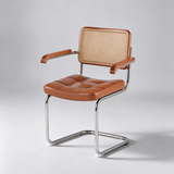 A modern accent chair with a tufted brown leather seat and backrest, a woven cane back panel, and curved chrome metal legs, shown on a light gray studio background.