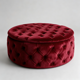 A round tufted velvet ottoman with a matching lid, upholstered in deep burgundy red velvet, photographed on a neutral light gray background.