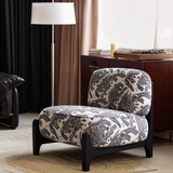 Ivory and black tiger-pattern accent chair beside a floor lamp and a cabinet with a record player.

