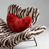Close-up of the zebra-print heart-shaped backrest, red heart cushion and curved upholstered seat edge.
