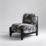 Ivory accent chair with black botanical upholstery, rounded cushions and a black frame, shown at a front angle.

