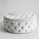 A round, tufted velvet ottoman with a matching lid, shown on a clean, light gray studio background.