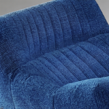 Close-up of a textured blue upholstered chair or sofa seat with channel tufting and ribbed fabric.