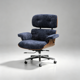 A modern lounge chair with deep blue velvet upholstery, a curved wooden frame, and a chrome five-star wheeled base, photographed on a light gray studio background.