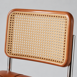 Close-up of a chair backrest with a warm brown wooden frame and a natural cane woven center, shown against a light gray background.