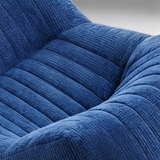Close-up of a blue ribbed upholstered chair or sofa arm, showing the fabric texture and curved padded contours.