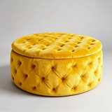 A round yellow velvet ottoman with a tufted lid, photographed on a clean light gray studio background.
