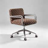 A modern office chair with a brown fabric upholstery patterned with white and light blue polka dots, featuring a polished chrome metal frame and five-star wheeled base, set against a neutral gray studio background.