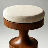 Close-up of the cream herringbone seat cushion on a warm brown wooden stool with a curved pedestal support.