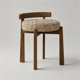 A wooden dining chair with a curved backrest, four tapered legs, and a round tufted seat cushion upholstered in a multicolor tweed fabric, shown against a neutral light gray background.