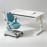 A modern children's desk and ergonomic chair set in a clean studio setting. The desk is white with a fold-out writing surface and side drawer, paired with a light blue and white adjustable ergonomic chair on wheels.