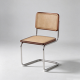 A modern cantilever dining chair with a curved chrome steel frame, a woven cane seat, and a woven cane backrest with dark brown wooden trim, photographed against a neutral light gray background.