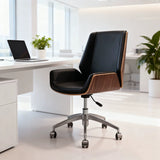 A modern office chair with black leather upholstery and a wood-grain side panel, positioned in a bright, contemporary office setting next to a white desk with a laptop.