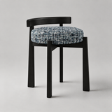 A modern dining chair with a black wooden frame and a round tufted seat cushion in a blue and white textured tweed fabric, photographed on a neutral light gray background.