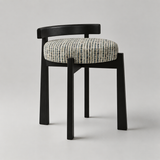 A modern dining chair with a black wooden frame and a round upholstered seat cushion featuring a textured blue, gray, and cream vertical stripe pattern, shown against a neutral light gray background.