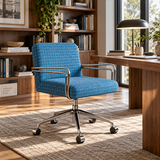 A blue and white checkered office chair with chrome metal armrests and a five-star wheeled base, positioned in a modern, sunlit home office next to a wooden desk.