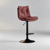 Dusty rose bar stool with a button-tufted backrest, padded seat, black pedestal base and oval footrest.