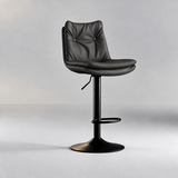 Charcoal black bar stool with a button-tufted backrest, layered padded seat and matching black pedestal base.