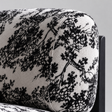 Close-up of ivory and black botanical backrest upholstery showing woven texture, rounded edges and piping.

