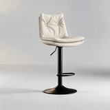 Ivory bar stool with a two-button tufted backrest, padded seat, black pedestal base and oval footrest.