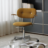 Mustard yellow upholstered office chair with a silver castor base beside a dark modular cabinet and sheer curtains.⠋

