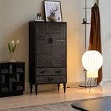 Black carved cabinet with double doors and lower drawers beside a glowing floor lamp in a styled living room.