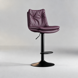 Dusty rose bar stool with a button-tufted backrest, padded seat, black pedestal base and oval footrest.