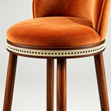 Close-up of the Alma bar stool's orange seat cushion, dark wood frame and cream openwork trim beneath the seat.
