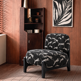 Black leopard-pattern accent chair in a wood-panelled room beneath black and white botanical wall art.