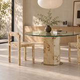 Two pale burl-patterned dining chairs beside a round glass table with a matching patterned pedestal base.
