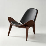 Lounge chair with black padded seat and backrest, a dark brown wood shell with upswept sides and three splayed legs.
