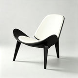 Lounge chair with cream padded seat and backrest, a black wood shell with upswept sides and three splayed legs.
